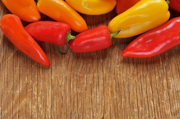 Peperoni dolci di diversi colori su un tavolo rustico — Foto Stock