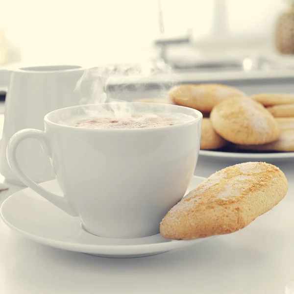 卡布奇诺咖啡和饼干在厨房的桌子上 — 图库照片