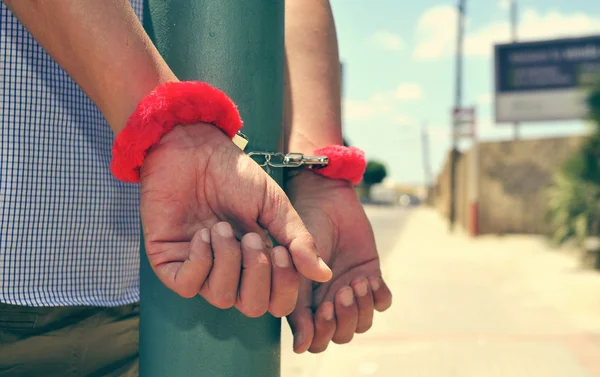 Ung man låst med fluffiga handbojor i en lyktstolpe — Stockfoto