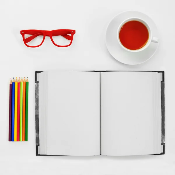 Colored pencils, blank notebook, eyeglasses and cup of tea on a — Stock Photo, Image