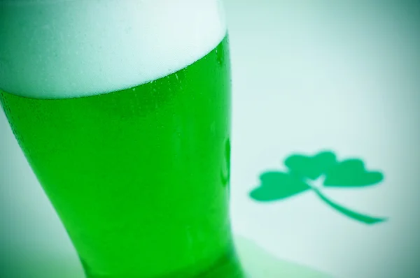 Стекло с крашеным зеленым пивом и трехлистным трилистником — стоковое фото