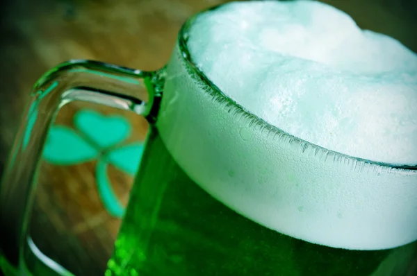 Becher mit gefärbtem grünen Bier und dreiblättrigem Shamrock — Stockfoto