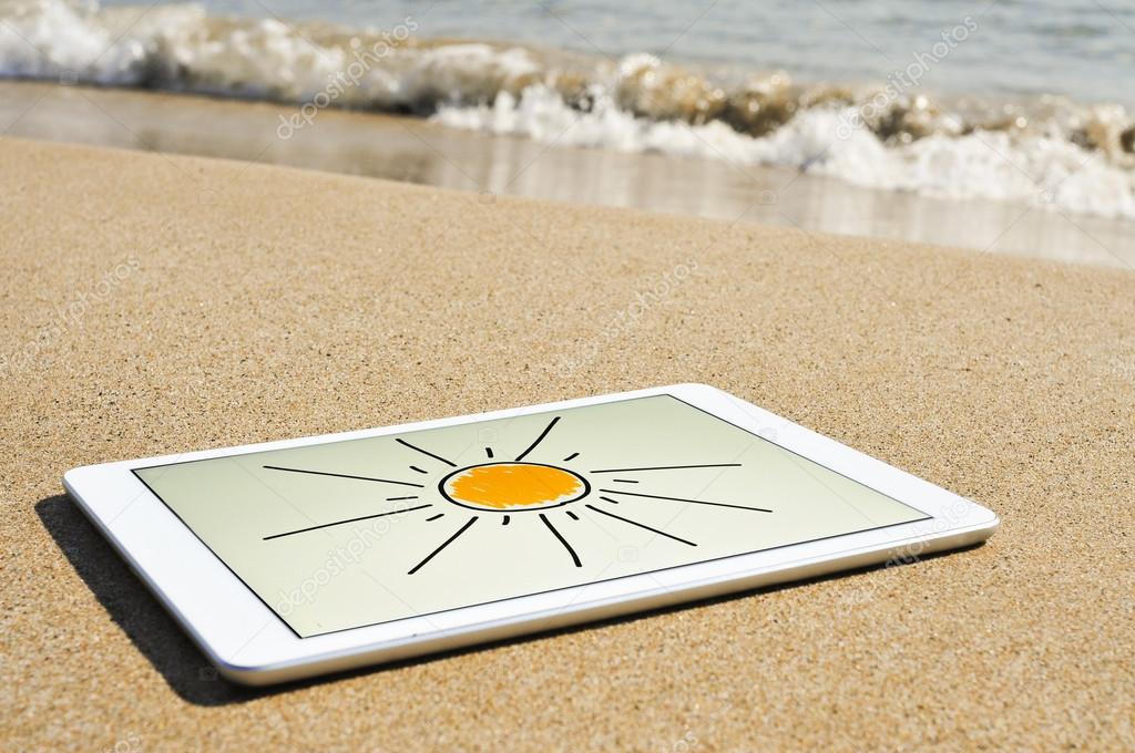 Sun drawn in a tablet in the sand of a beach