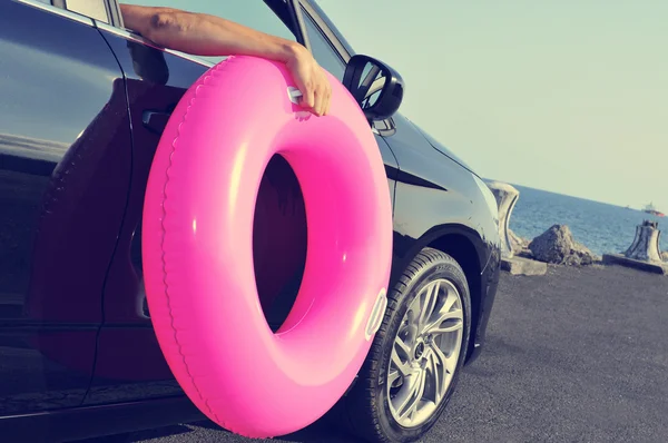 Homem segurando um anel de natação fora de um carro — Fotografia de Stock