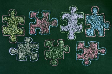 Bir kara tahta üzerinde farklı renkteki puzzle parçaları