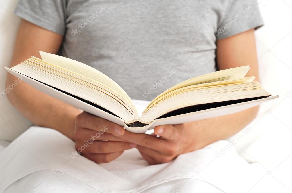 Young man reading a book in bed