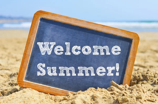 Texto bienvenido verano en una pizarra, en la arena de una playa —  Fotos de Stock