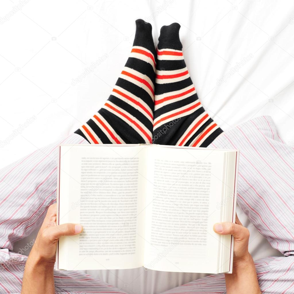 young man reading a book in bed