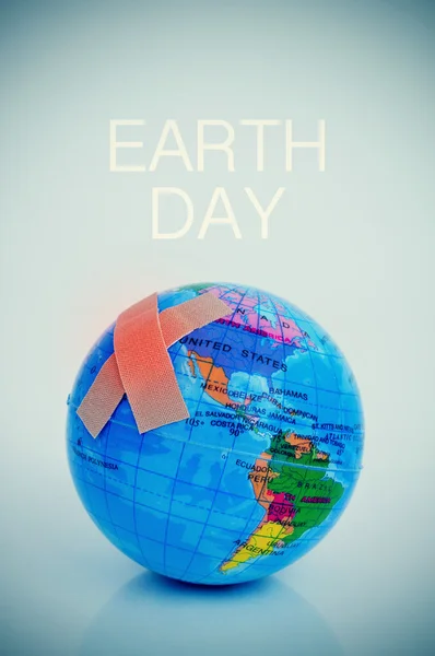Adhesive bandages on a terrestrial globe and the text earth day — Stock Photo, Image