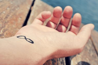 young man with an infinity symbol tattooed in his wrist clipart
