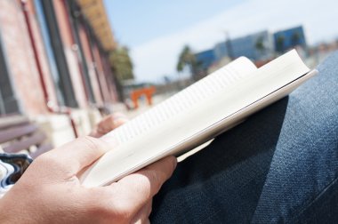 young man reading a book outdoors clipart