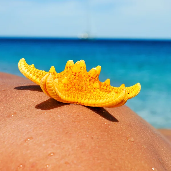 Starfish on the back of a young man  on the beach — Stock Photo, Image