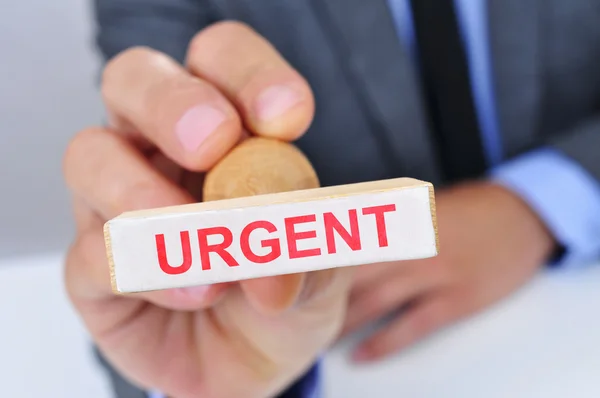 Hombre con un sello de goma con la palabra urgente — Foto de Stock