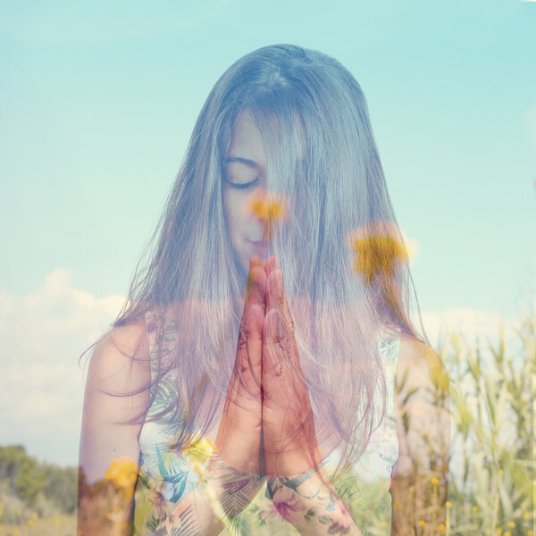 double exposure of a young woman meditating and a peaceful lands
