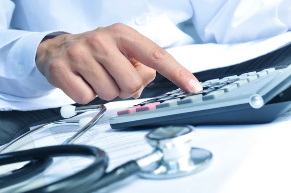 Profesional sanitario calculando en una calculadora electrónica —  Fotos de Stock