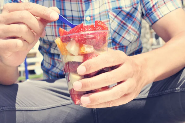 Młody mężczyzna jedzenie owoców sałatka na zewnątrz — Zdjęcie stockowe