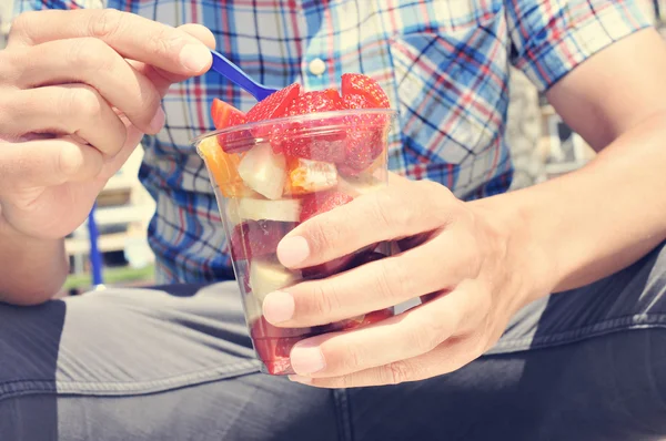 Junger Mann isst Obstsalat im Freien — Stockfoto