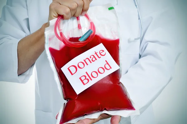 Doctor holding a blood bag with the text donate blood — Stock Photo, Image