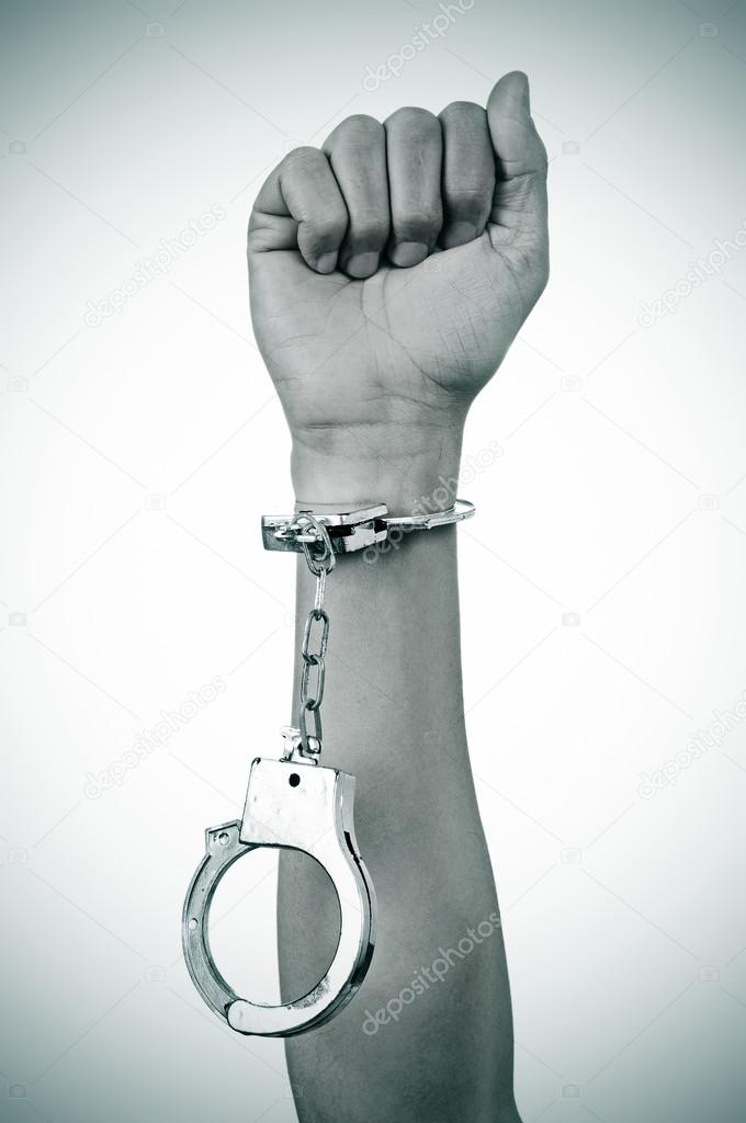 raised fist of a man with a handcuff in his wrist
