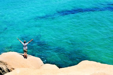 man with the arms in the air in front of the ocean
