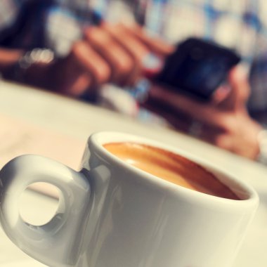 Man with a cup of coffee using a smartphone in the terrace