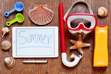 Word summer written in a tablet and summer stuff