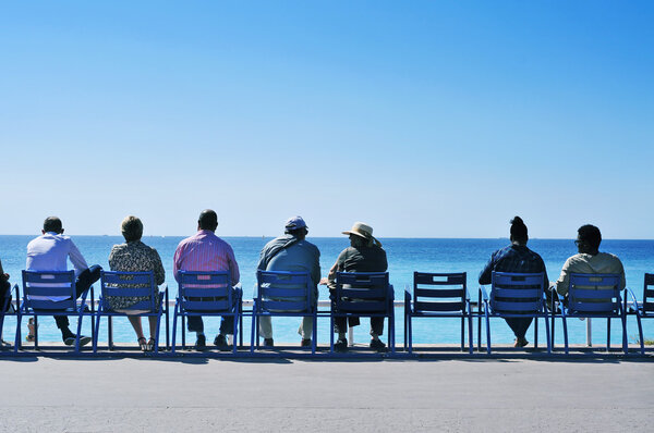 people sitting facing the sea at the Promenade des Anglais in Ni