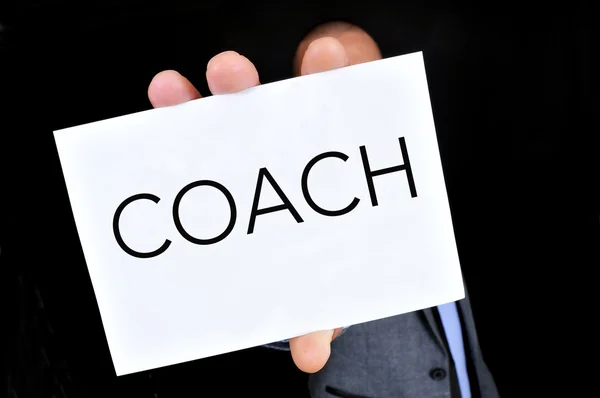 Young man with a signboard with the word coach — Stock Photo, Image