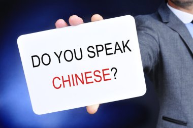man showing a signboard with the question do you speak chinese? clipart