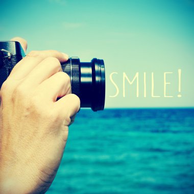 man taking a picture and the text smile!, with a retro effect clipart