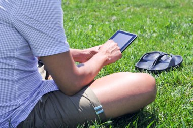 young man using a tablet computer in a park