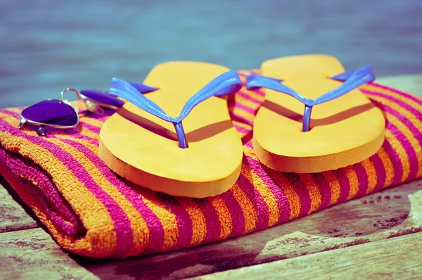 Sunglasses, flip-flops and beach towel, on a wooden boardwalk — ストック写真