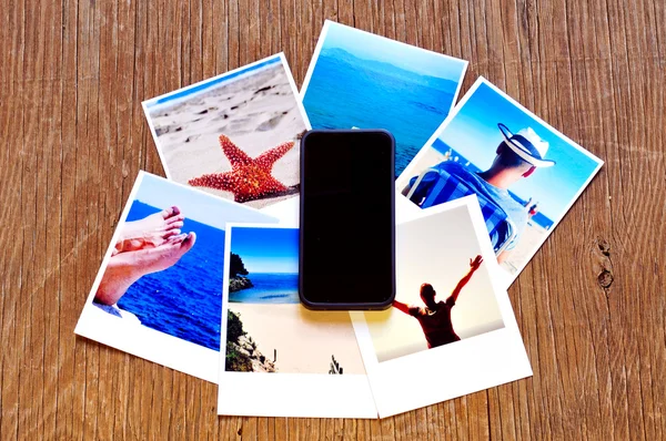 Smartphone e alcune foto su una superficie di legno — Foto Stock