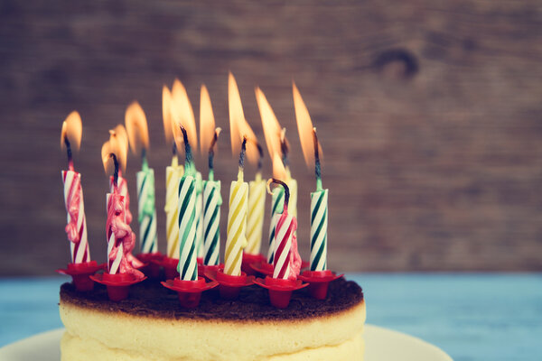 Velas de cumpleaños encendidas en un pastel de queso, con un efecto retro — Imagen de stock Velas de cumpleaños encendidas en un pastel de queso, con un efecto retro Imágenes De Stock Sin Royalties Gratis