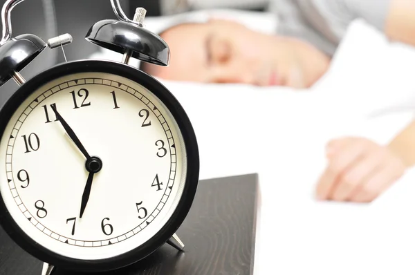 Alarm clock and young man sleeping in bed — Stock Photo, Image