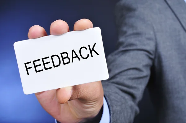 Uomo in giacca e cravatta mostra un cartello con la parola feedback — Foto Stock