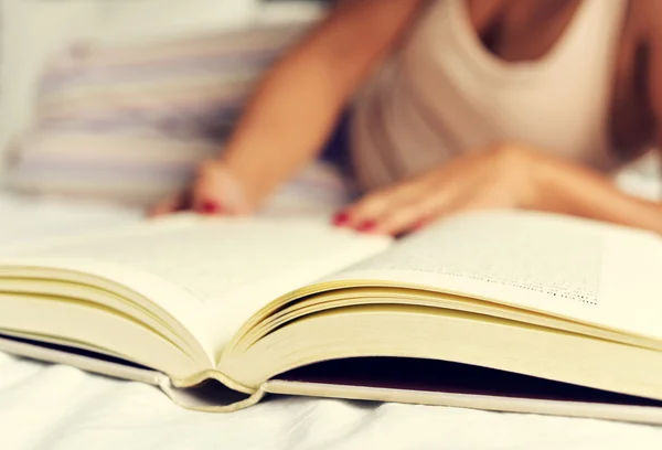 Genç bir kadın yatakta kitap okuyor. — Stok fotoğraf