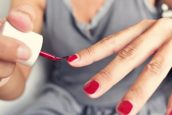 Молода жінка наносить червоний лак для нігтів на нігті — стокове фото