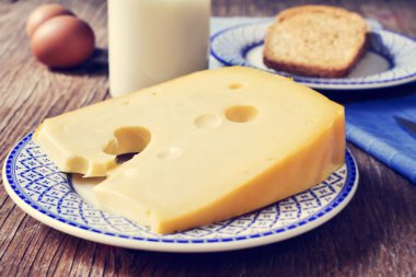 Cheese, milk, eggs and bread on a rustic wooden table