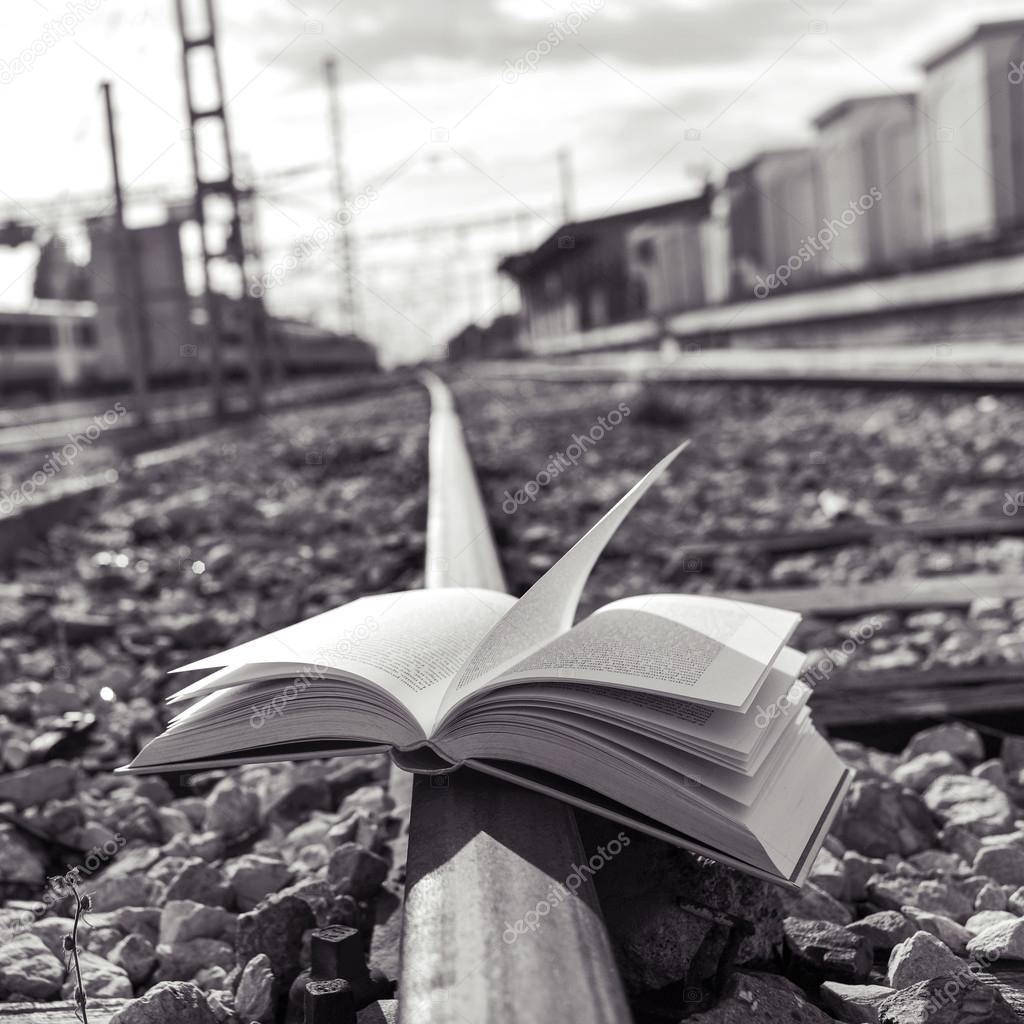 book on the railroad tracks, black and white