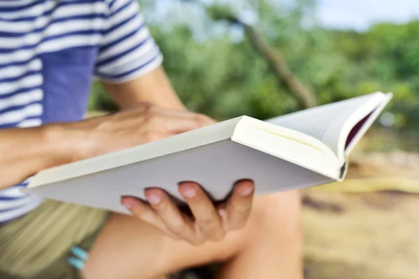 Jonge man lezen van een boek buitenshuis — Stockfoto