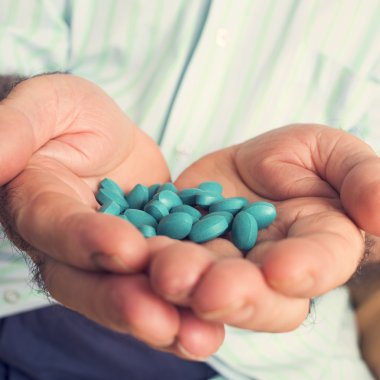 old man with a pile of blue pills in his hand clipart