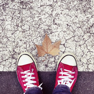 dry leaf on the asphalt and the feet of a young man