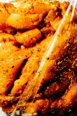 marinated chicken pieces covered with paprika and herbs inside a plastic container, the shiny texture highlighting the Andalusian preparation for pinchos morunos