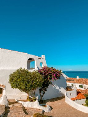 La Almadrava 'da beyaz yıkanmış Akdeniz evleri, Hospital del Infant, İspanya, derin mavi bir gökyüzünün altında ve aydınlık gün ışığında sakin denizle karşı karşıya.