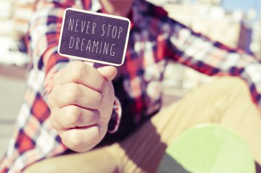 young man with a signboard with the text never stop dreaming clipart