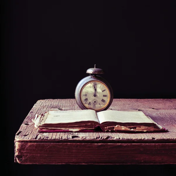 Old alarm clock and book on a rustic wooden table — Stock Photo, Image