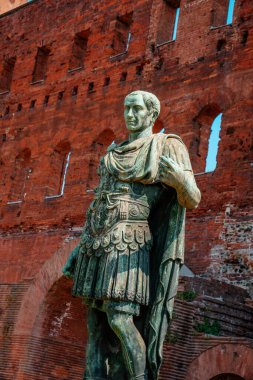İtalya 'nın Torino kentindeki Porta Palatina' nın önündeki Sezar Augustus heykelinin yakın görüntüsü. İmparator detaylı zırh ve Roma harabelerine karşı duran örtülü bir pelerin giymişti.