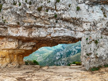 La Forada boyunca panoramik bir manzara, Serra del Montsia, İspanya 'da delinmiş kaya kemeri, doğal taşların altındaki yeşil vadileri ve engebeli uçurumları ortaya çıkarıyor.
