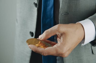 Elinde altın para jetonları tutan takım elbiseli bir adam. Dijital para birimini, kripto para birimini ve modern finans birimini simgeliyor.